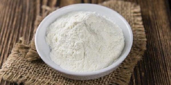 White powder in a bowl on a rustic surface.