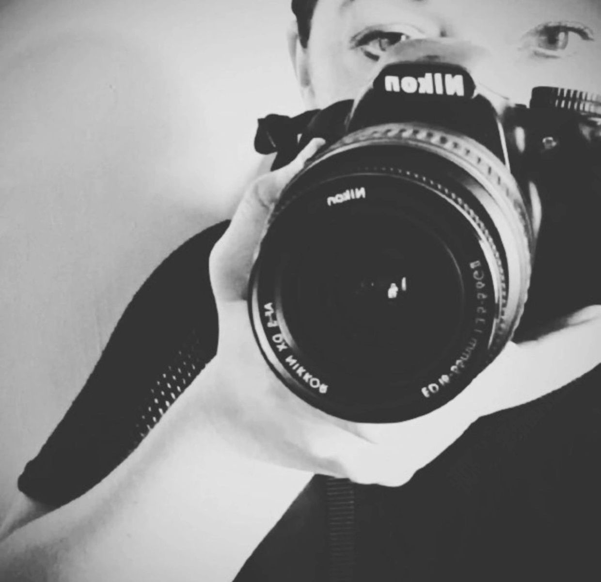 Person holding a Nikon camera in a black-and-white photo.