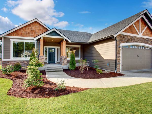 Modern suburban house with a manicured lawn and stone-accented exterior.
