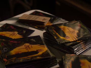 Stacks of promotional flyers on a table under dim lighting.