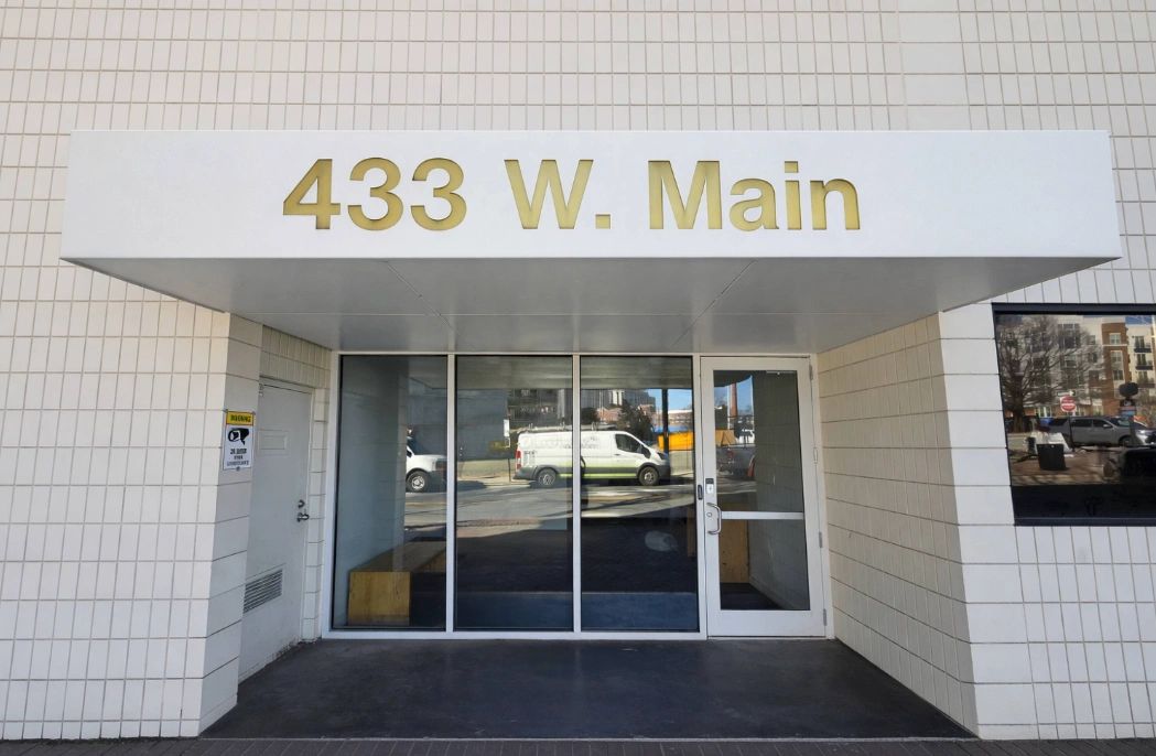Entrance to 433 W. Main building with glass doors and white tiled walls.