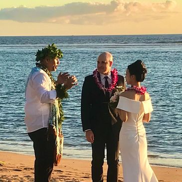 Hawaii officiant during beach wedding ceremony sunset time with tropical flowers