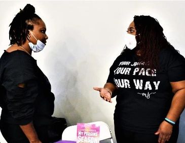 Two women wearing masks engaged in conversation indoors.