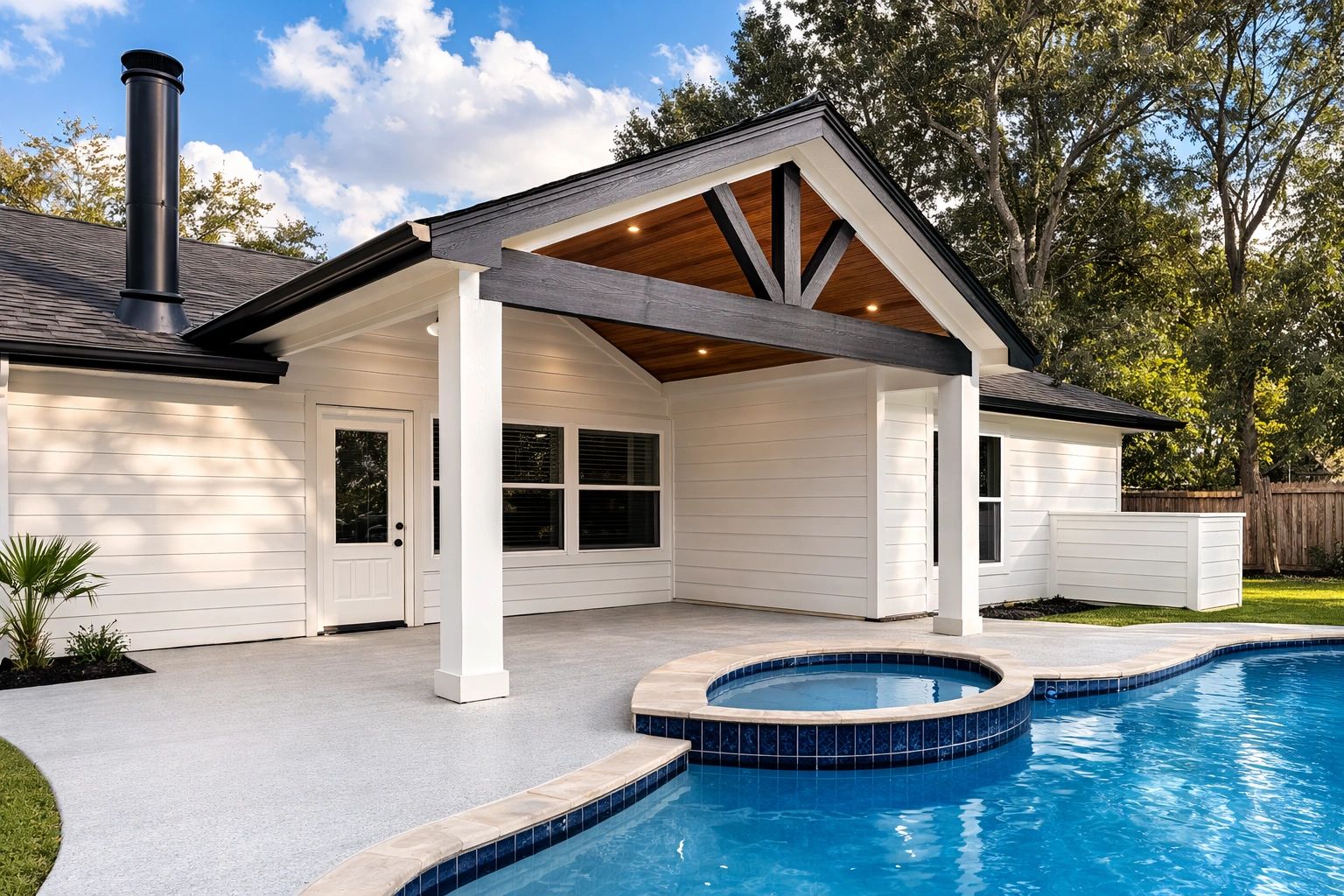 Modern backyard with a covered patio and swimming pool under a blue sky.