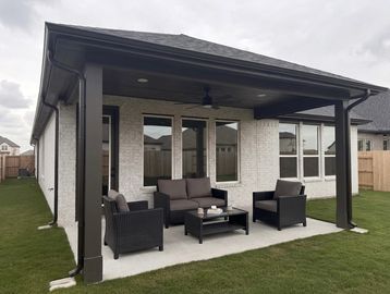 Modern backyard patio with black outdoor furniture under a covered porch.