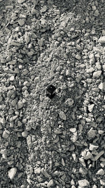 A model police telephone box sat atop a large expanse of grey rubble in black and white.