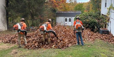 Three workers blowing leaves with backpack blowers. 