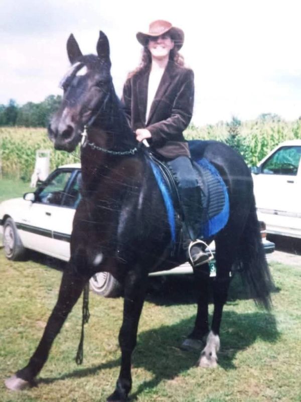 Person in cowboy hat riding a black horse.