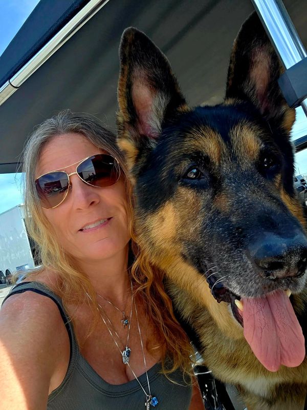 Woman with sunglasses taking a selfie with a German Shepherd dog.