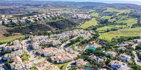 Aerial view of a suburban neighborhood surrounded by green hills and open land.