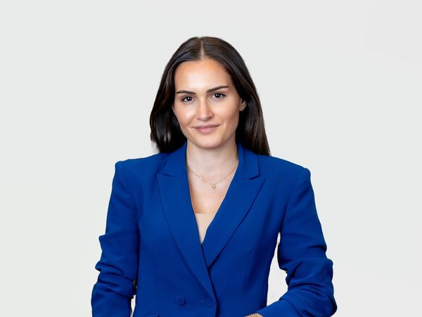 Confident woman in a blue blazer posing against a white background.