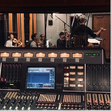 Music recording session with conductor and musicians.