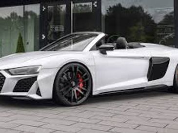 White convertible sports car parked outside a modern building.
