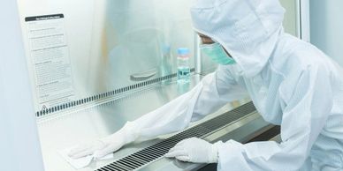 Scientist cleaning a sterile lab environment wearing protective gear.