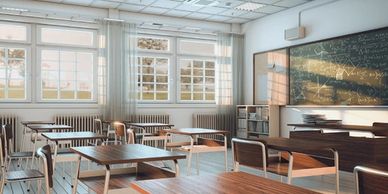 Bright, empty classroom with wooden desks and large windows.