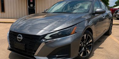 Sleek gray Nissan sedan parked outside on a sunny day.