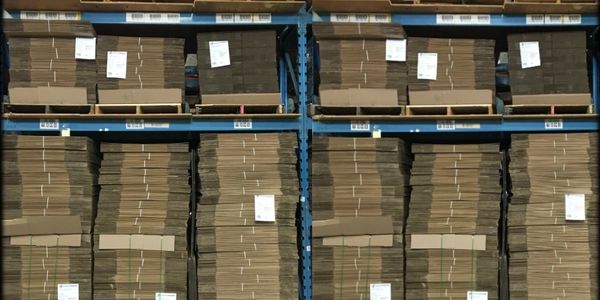 Stacks of cardboard sheets neatly organized on warehouse shelves.