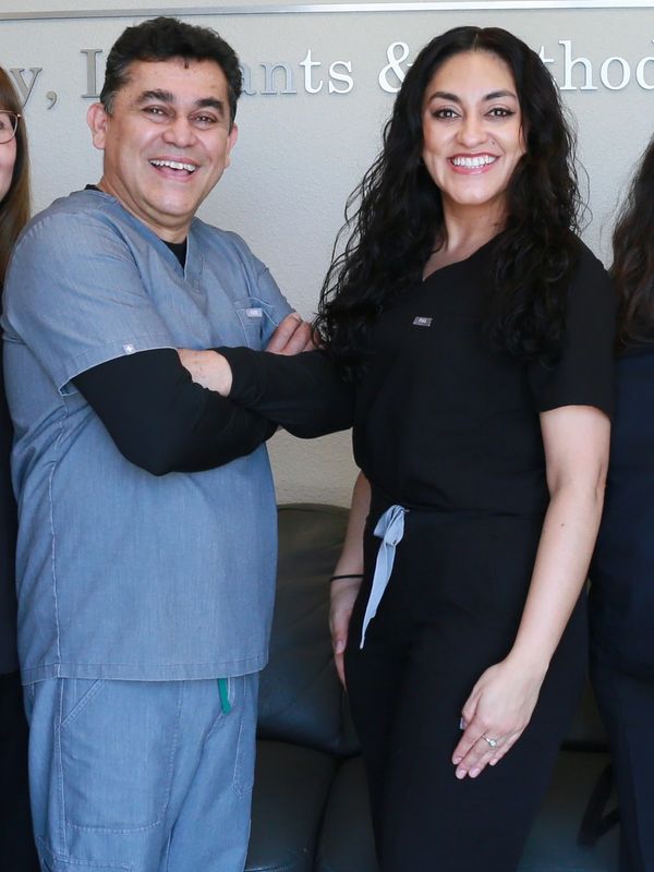 Two smiling medical professionals in scrubs standing together indoors.