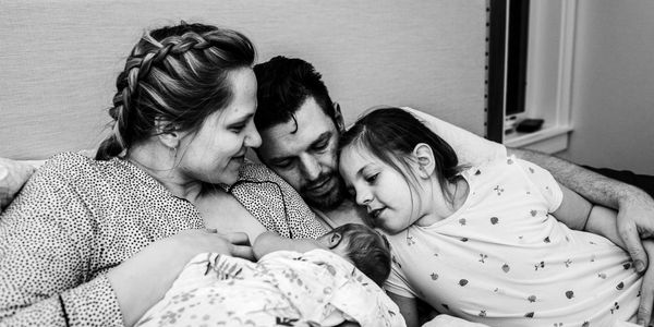 A family admiring a newborn after the homebirth with a midwife