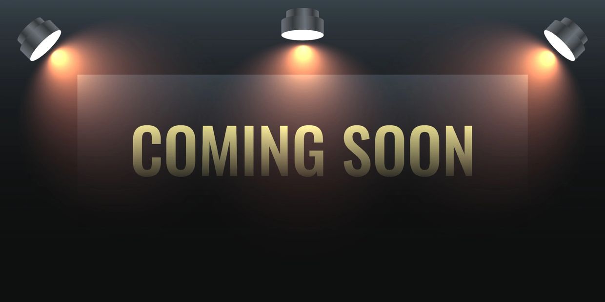 A stylish 'Coming Soon' sign illuminated by three spotlights.