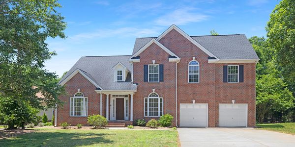 Large brick two-story house with a double garage and front yard.