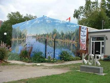 A large painted canvas announcing an art show wrapped around a building in Waterloo, Ontario