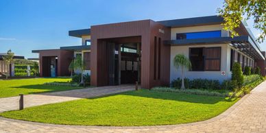 Modern building with brown wooden accents and well-maintained lawn under a clear blue sky.