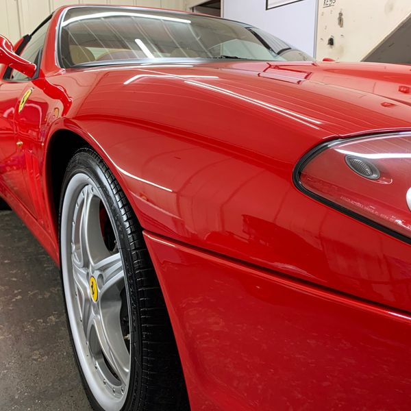 Close-up of a shiny red Ferrari front side and wheel.