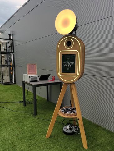 A vintage-style photo booth with a glowing ring light and a tripod stand.