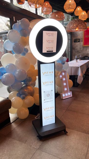 Photo booth with ring light and balloon decoration at an event venue.