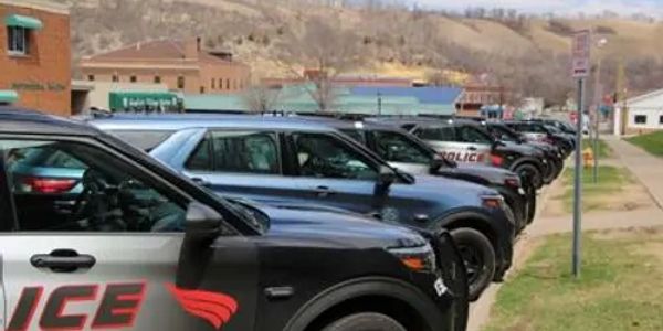 A lineup of police vehicles parked side by side in a small town.