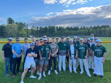 A group of young men posing on a baseball field with clear skies.
