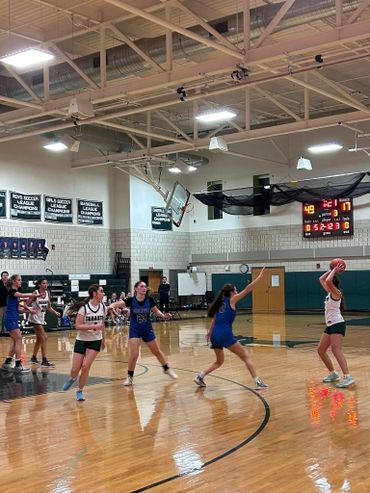 High school girls' basketball game with active defense and offense.