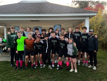Youth soccer team posing together in front of a pavilion outdoors.