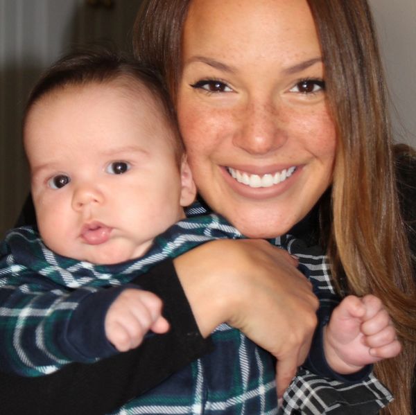 A smiling woman holds a baby in a warm embrace.
