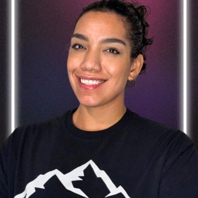 Smiling woman in black shirt with mountain graphic.