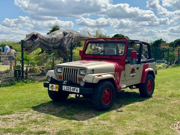 JP04 Jurassic Park Jeep parked near a T-Rex model at a dinosaur park