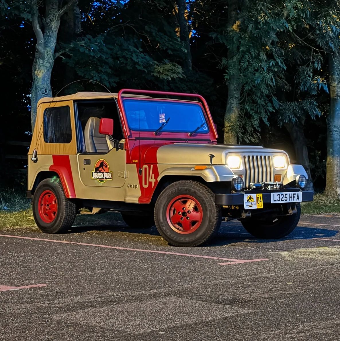 JP04 Jurassic Park Jeep with headlights on parked near trees at dusk