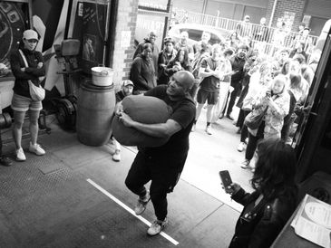 Man lifting a heavy stone in front of a crowd.