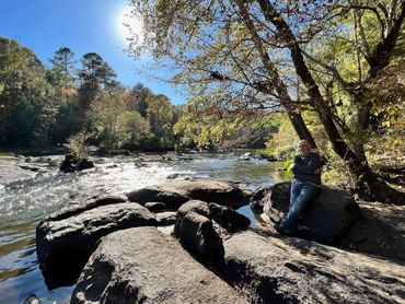 Man sitting on rocks by a stream/creek enjoying nature. 