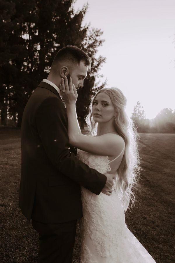 Couple embracing at sunset in wedding attire.