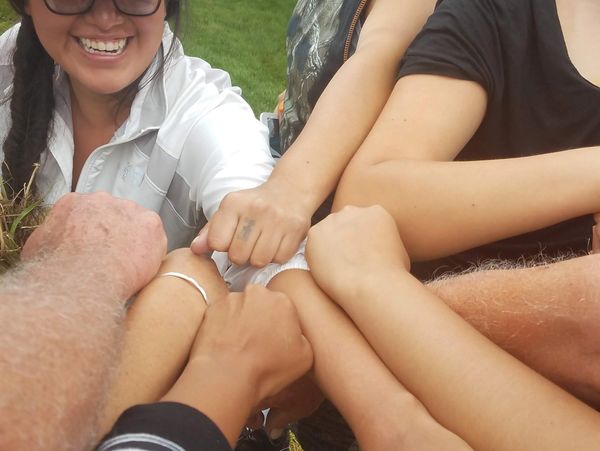 Group of native american women witth Caucasian allys putting their arms together. 