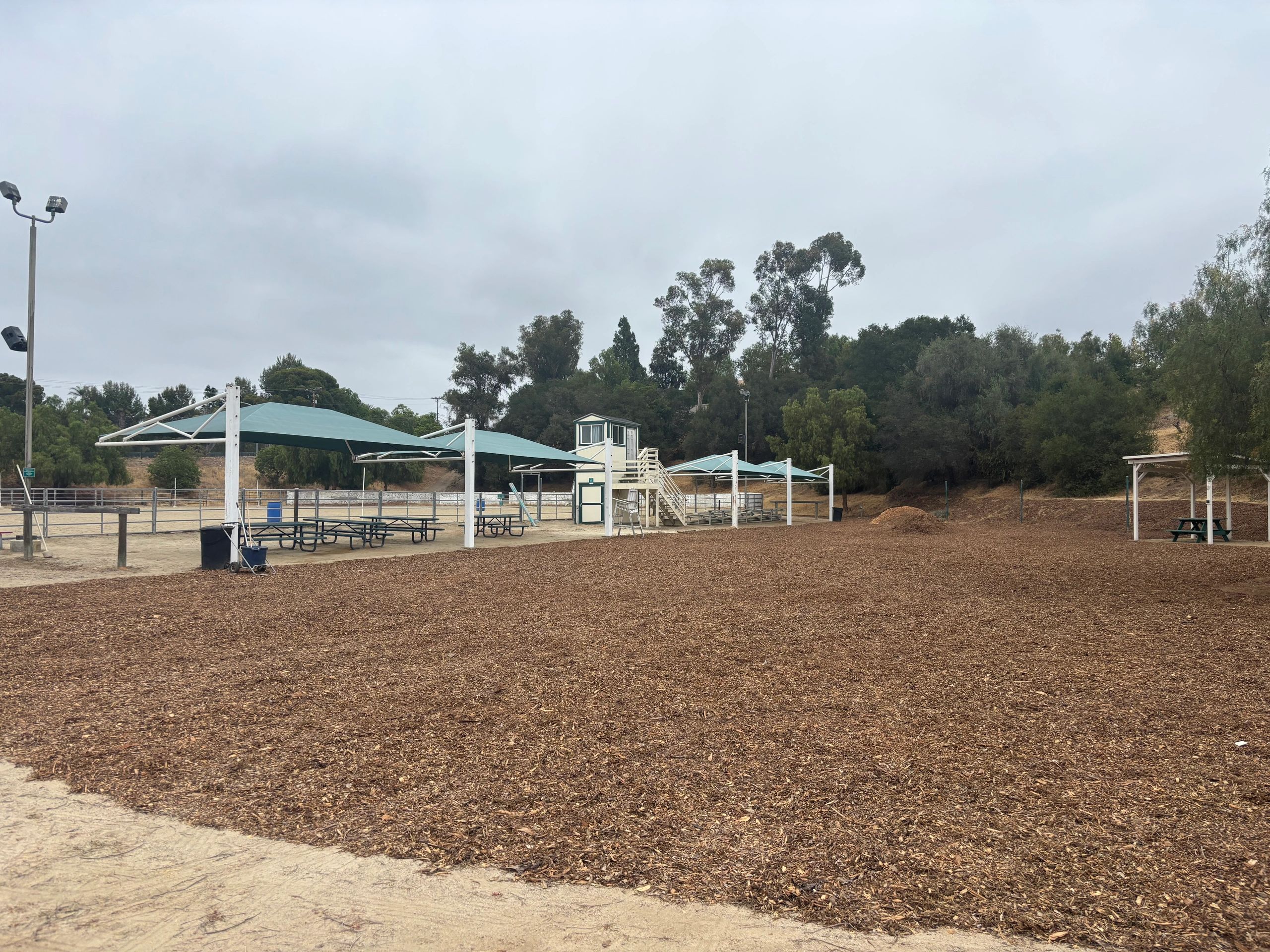 Wide area covered in fresh wood chip mulch with shade structures in Orange County