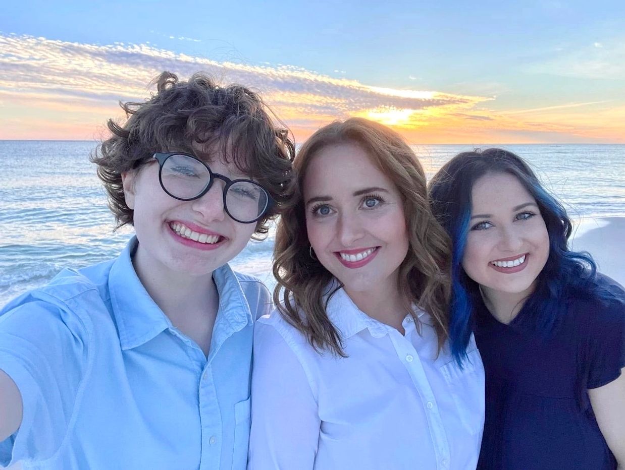 Aron Yellott, Graham Yellott and Mia Yellott smiling on the beach at sunset