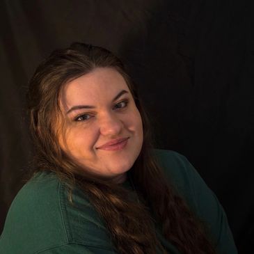 Smiling woman with long hair against a dark background.