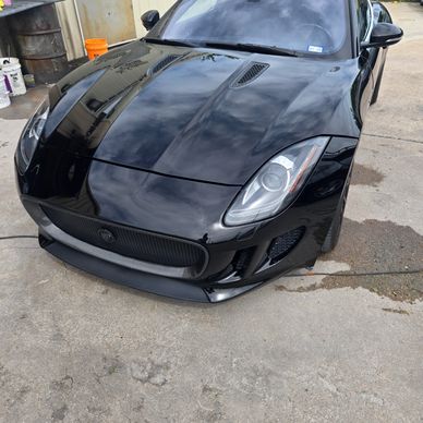 Sleek black sports car parked on concrete outdoors.