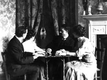 Four people sitting at a table in a vintage room.