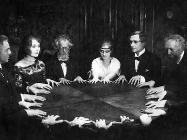People gathered around a table performing a séance.