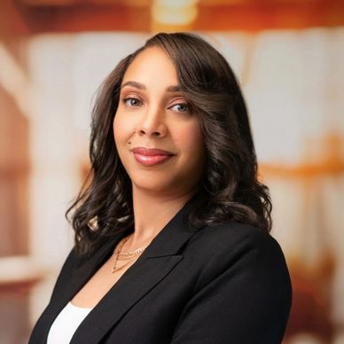 Confident woman in professional attire posing indoors with a warm smile.