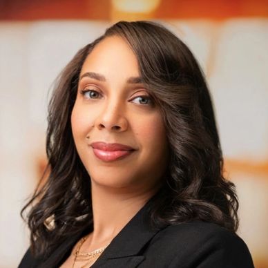 Confident woman in professional attire posing indoors with a warm smile.